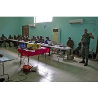 Dans une salle de formation, des stagiaires béninois et sénégalais écoutent le cours sur le droit des conflits armés dispensé par un commandant ivoirien instructeur, à l'aide d'un rétroprojecteur.