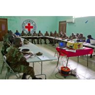 Dans une salle de formation, ornée du drapeau du CICR (comité international de la Croix-Rouge), des stagiaires béninois et sénégalais écoutent le cours.