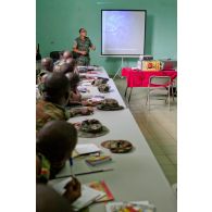Dans une salle de formation, des stagiaires béninois et sénégalais écoutent le cours sur le droit des conflits armés, dispensé par un commandant ivoirien instructeur, à l'aide d'un rétroprojecteur.