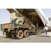 Déchargement d'un camion 6x6 TPK6 ALM ACMAT  togolais armé d'un canon de DCA ZPU-4 quadritube de calibre 14,5 mm bâché de la soute ouverte d'un avion cargo de transport militaire C-17 canadien sur l'aéroport de Bamako.