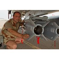 Portrait d'un adjudant-chef de l'armée de l'Air, chef des armuriers sur avions de combat Mirage-2000D, au montage de bombes SAMP (sol-air moyenne portée) sous aile.