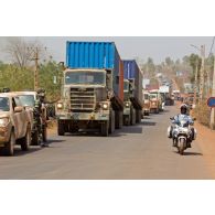 Arrivée de véhicules pick-up 4x4 Toyota Landcruiser transport de troupes et de camions porte-containers CCC AM General du convoi sénégalais, sous escorte d'un motard malien. Les soldats sont armés de fusils d'assaut Colt M4-A1 et d'une mitrailleuse Saco M60.