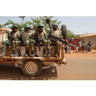 Portrait de militaires sénégalais sur un véhicule pick-up 4x4 Toyota Landcruiser transport de troupes du convoi sénégalais, arrivant sous le regard d'habitants maliens. Les soldats sont armés de fusils d'assaut Colt M16-A2, d'une mitrailleuse Saco M60, et d'un fusil Galil avec lance-grenade M203 monté.