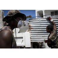 Des stagiaires du Service militaire adapté (SMA) déblayent les déchets qui encombrent une rue du quartier de Sandy Ground à Marigot sur l'île de Saint-Martin, aux Antilles.