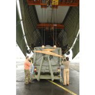 Préparation du chargement d'une remorque de cuisines de campagne dans l'avion cargo Antonov 124-100 par les membres d'équipage de l'avion.