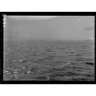 En mer. Lancement d'une torpille par un sous marin sur but fixe (le sillage sur l'eau). A gauche, le but fixe visé par la torpille. [légende d'origine]