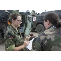 Un médecin des armées de l'équipe médicale française s'entretient avec un superviseur allemand au terme d'un exercice sanitaire au sein du camp de Pabradé, en Lituanie.