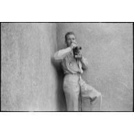 Portrait en pied d'Arthur Smet en extérieur, avec un appareil photo dans les mains. [légende d'origine]