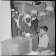 [Un Algérien dépose son bulletin de vote dans une urne à la mairie de Wagram.]