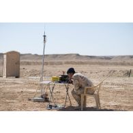 Un élément du 107e bataillon d'artillerie de l'armée irakienne, au poste de radionavigateur, est en liaison radio afin de coordonner les salves de tir lors d'une instruction sur le site de la base aérienne AAAB (Al-Asad Air Base).