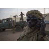 Portrait d'un soldat malien en communication par talkie-walkie lors d'une patrouille dans les rues de Ménaka.