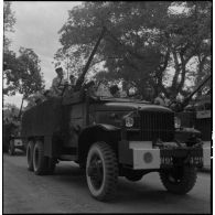 Des GMC blindés transportant des canons antiaériens passent devant la tribune officielle lors du 14 juillet 1951 à Hanoï.