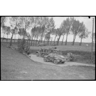 Durant la bataille de Gembloux, une automitrailleuse Sd.kfz.222 passe devant un tracteur d'artillerie Sd.kfz.8 et son obusier 10,5 cm Feldhaubitze 18, tous de la 4e division blindée allemande (4.Panzer-Division).