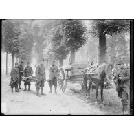 Les soldats du 104e RI transportent un blessé sur un brancard, on distingue une voiture attelée modèle 1888. [légende d'origine]