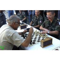 Un militaire de la KFOR joue aux échecs avec une personne handicapée.