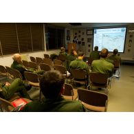 Briefing de préparation de mission pour l'équipage et les opérateurs navigants d'un avion E3F du 36e EDCA (escadron de détection et de contrôle aéroporté) présenté par un capitaine féminin sur la base d'Avord à l'aide d'une carte de Libye.