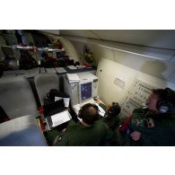 Portrait d'un sergent opérateur d'ESM (electronic support measure ou système d'écoute d'émissions) devant son écran radar aux côtés d'un adjudant-chef et d'un technicien radar, lors d'une mission de contrôle aérien sur la Libye à bord d'un avion de détection Awacs.