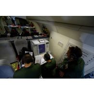 Portrait d'un sergent opérateur d'ESM (electronic support measure ou système d'écoute d'émissions) devant son écran radar aux côtés d'un adjudant-chef et d'un technicien radar, lors d'une mission de contrôle aérien sur la Libye à bord d'un avion de détection Awacs.