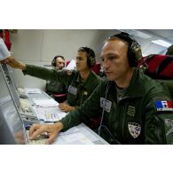 Portrait du lieutenant-colonel Arnaud Bourguignon, chef de mission E3F (tactical director), à son poste aux côtés d'un capitaine et d'un adjudant, lors d'une mission de contrôle aérien sur la Libye à bord d'un avion de détection Awacs.
