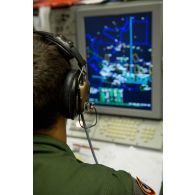 Portrait d'un sergent opérateur d'ESM (electronic support measure ou système d'écoute d'émissions) devant son écran radar, lors d'une mission de contrôle aérien sur la Libye à bord d'un avion de détection Awacs.