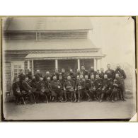 [Portrait de groupe d'officiers russes assis devant une maison traditionnelle en bois].