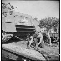 En gare de Boufarik, des soldats français arriment sur un wagon porte-chars un char moyen sherman M4 A4 américain, destiné au 5e RCA (régiment de chasseurs d'Afrique) de la 1re DB (division blindée).