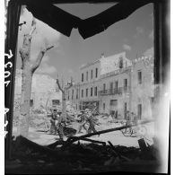 Des civils rentrent dans Bizerte en ruine sous la protection de soldats du CFA (Corps franc d'Afrique).