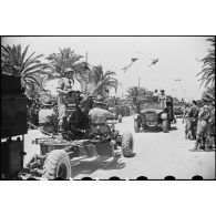 Défilé de camions de l'artillerie britannique tractant des canons antiaériens Bofors de 40 mm, lors de la cérémonie célébrant la victoire alliée à l'issue de la campagne de Tunisie.
