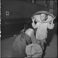 Sur un quai de la gare d'Hanoï, un enfant garde des bagages.