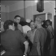 Lors d'une visite médicale organisée au retour des officiers supérieurs prisonniers à Diên Biên Phu, un prisonnier de guerre discute avec des officiers et deux femmes.