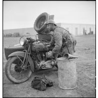 Un motocycliste d'un groupe de reconnaissance vidange le réservoir de sa moto René Gillet  type G1 (caisse de type dragons portés de marque Bernardet) dans le secteur de Bou Arada.