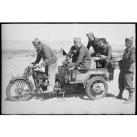 Des soldats du FSEA (Front sud-est algérien) essaient une Moto-Guzzi Trialce de l'armée italienne, moto transformée en tricycle, récupérée dans le désert au nord du Chott el Jerid.