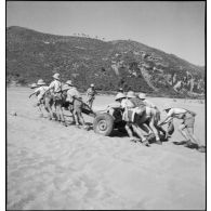 Sur une plage, à l'issue d'une instruction de tir sur cibles mobiles, des élèves aspirants ramènent un canon antichar de 25 mm modèle 1934.