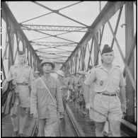 Un soldat de l'APVN (Armée populaire vietnamienne) et deux officiers du CEFEO (Corps expéditionnaire français en Extrême-Orient) devant le pont Paul-Doumer (aujourd'hui Long Biên).