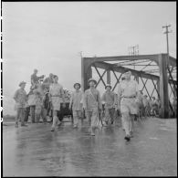 Des soldats de l'APVN (Armée populaire vietnamienne) et deux officiers du CEFEO (Corps expéditionnaire français en Extrême-Orient) devant le pont Paul-Doumer (aujourd'hui Long Biên).