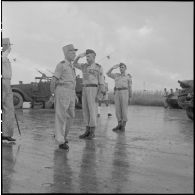 Sur un aérodrome d'Hanoï, le général Cogny (à gauche) et le général Salan (au centre) passent des troupes motorisées et blindées en revue.