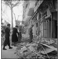 Des civils sortant d'un abri souterrain après le bombardement allemand visant l'aérodrome Maison-Blanche à Alger, dans la nuit du 20 au 21 novembre 1942, reviennent dans leur immeuble endommagé rue d'Isly.