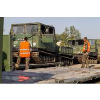 Des soldats guident le chargement de véhicules articulés chenillés (VAC) Bandvagn 206 à bord d'un camion porteur polyvalent logistique (PPLOG) à Jõhvi, en Estonie.