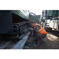 Un soldat fixe les chenilles d'un véhicule articulé chenillé (VAC) Bandvagn 206 à la plateforme d'un camion porteur polyvalent logistique (PPLOG) à Jõhvi, en Estonie.