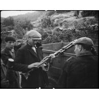 Des partisans corses examinent du matériel abandonné par les Allemands et entreposé dans un camion : des casques, une MG-34 et son chargeur circulaire.