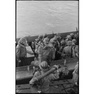 Des fantassins français embarquent à bord d'un LCVP conduit par un soldat américain.