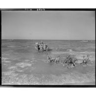 Depuis un LCVP, des soldats français débarquent sur une plage.