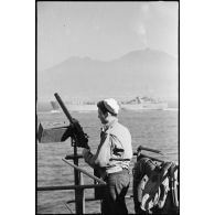 Un marin américain, servant d'une mitrailleuse antiaérienne, est à son poste de combat à bord d'un landing ship tanks qui approche des côtes italiennes.