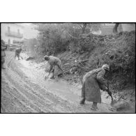 Des pionniers dégagent la boue sur une route.