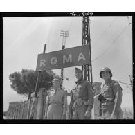 Le lieutenant general Mark Wayne Clark, commandant la Ve armée américaine, pose symboliquement avec deux de ses grands subordonnés devant un panneau indicateur aux portes de Rome libérée ; à droite, le major general Geoffrey Keyes, commandant le IIe corps d'armée.