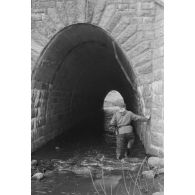 Traversée d'un tunnel par un sous-officier allemand armé d'un pistolet-mitrailleur MP-40.