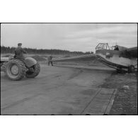 Sur la piste du terrain d'aviation, un tracteur agricole tracte le planeur DFS-230 du Luftlandegeschwader 1 (8./LLG 1) vers un nouvel emplacement.