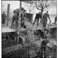 Des soldats (sapeurs ou pionniers) coulent le béton spécial pour la construction d'un ouvrage fortifié de la ligne Maginot.
