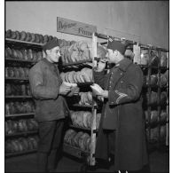 Un sergent de carrière (double galonnage en fer de lance sur la manche) contrôle la qualité du pain produit par une boulangerie militaire.