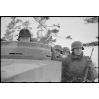 Chargés de fantassins, des chars lourds Tiger du schwere Panzer-Abteilung 505 progressent.